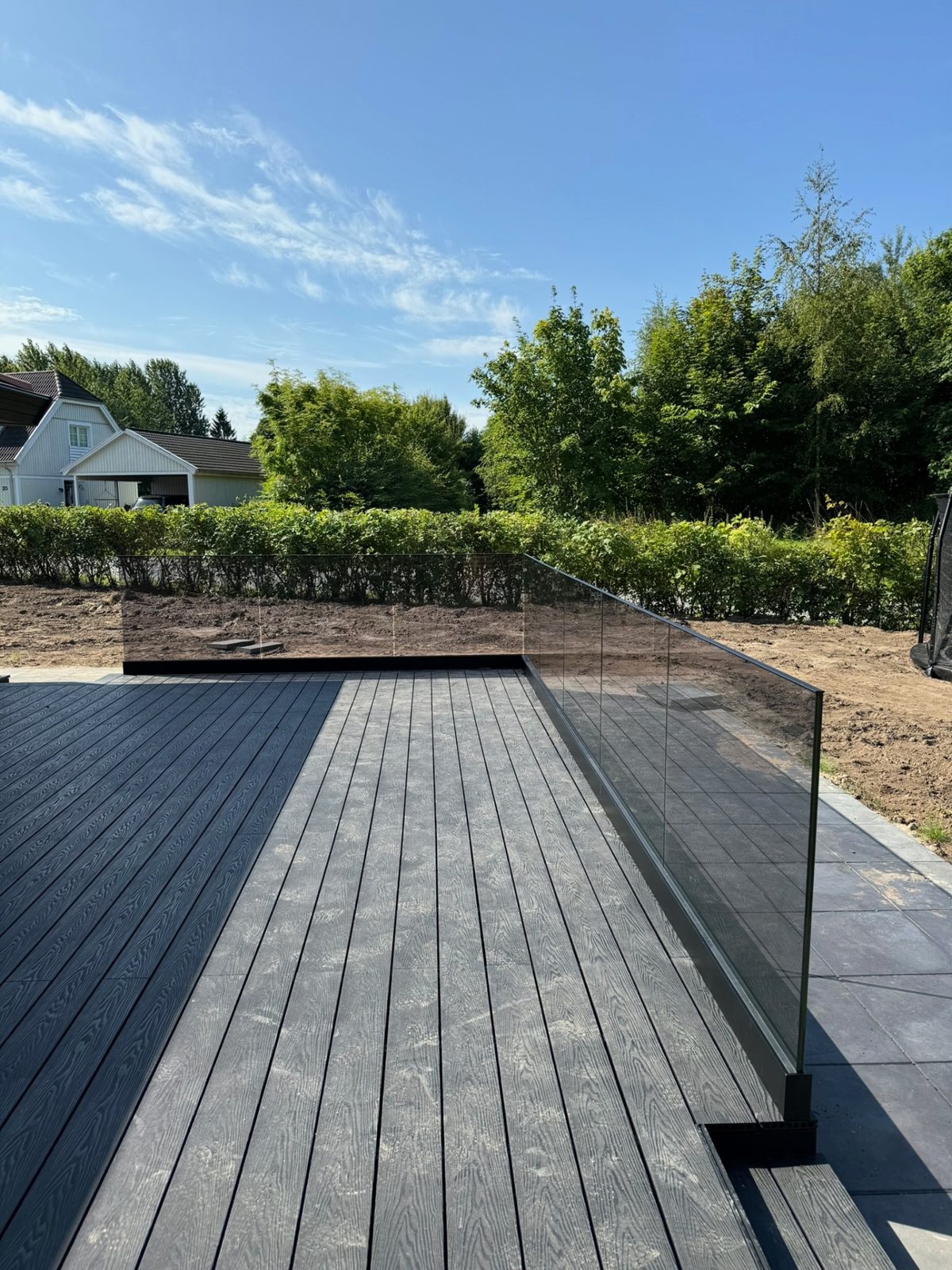 Rammeløst glasværn omkring stor terrasse i composit
