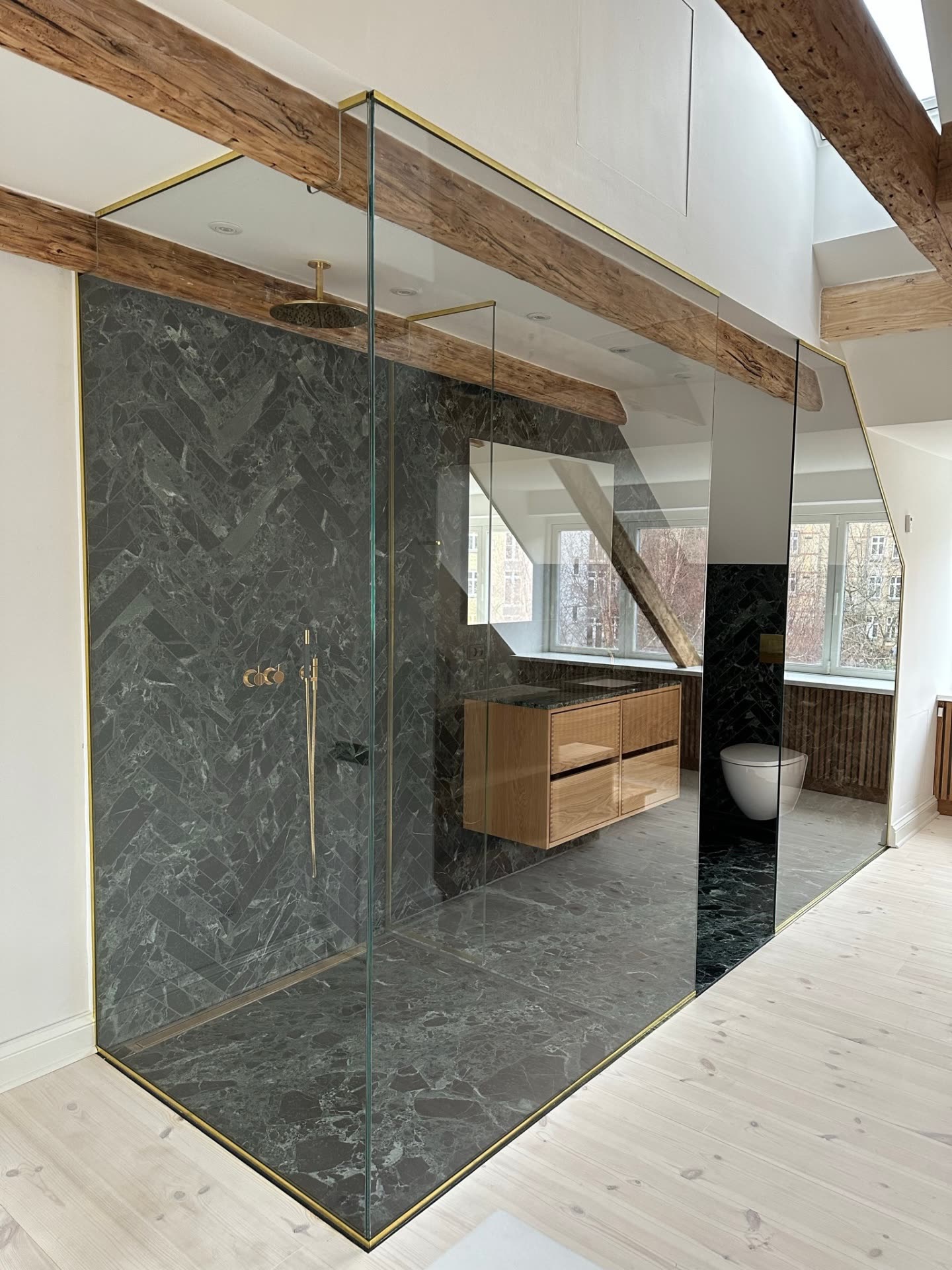 Glasvæg fra gulv til loft med messingkanter og marmorflise